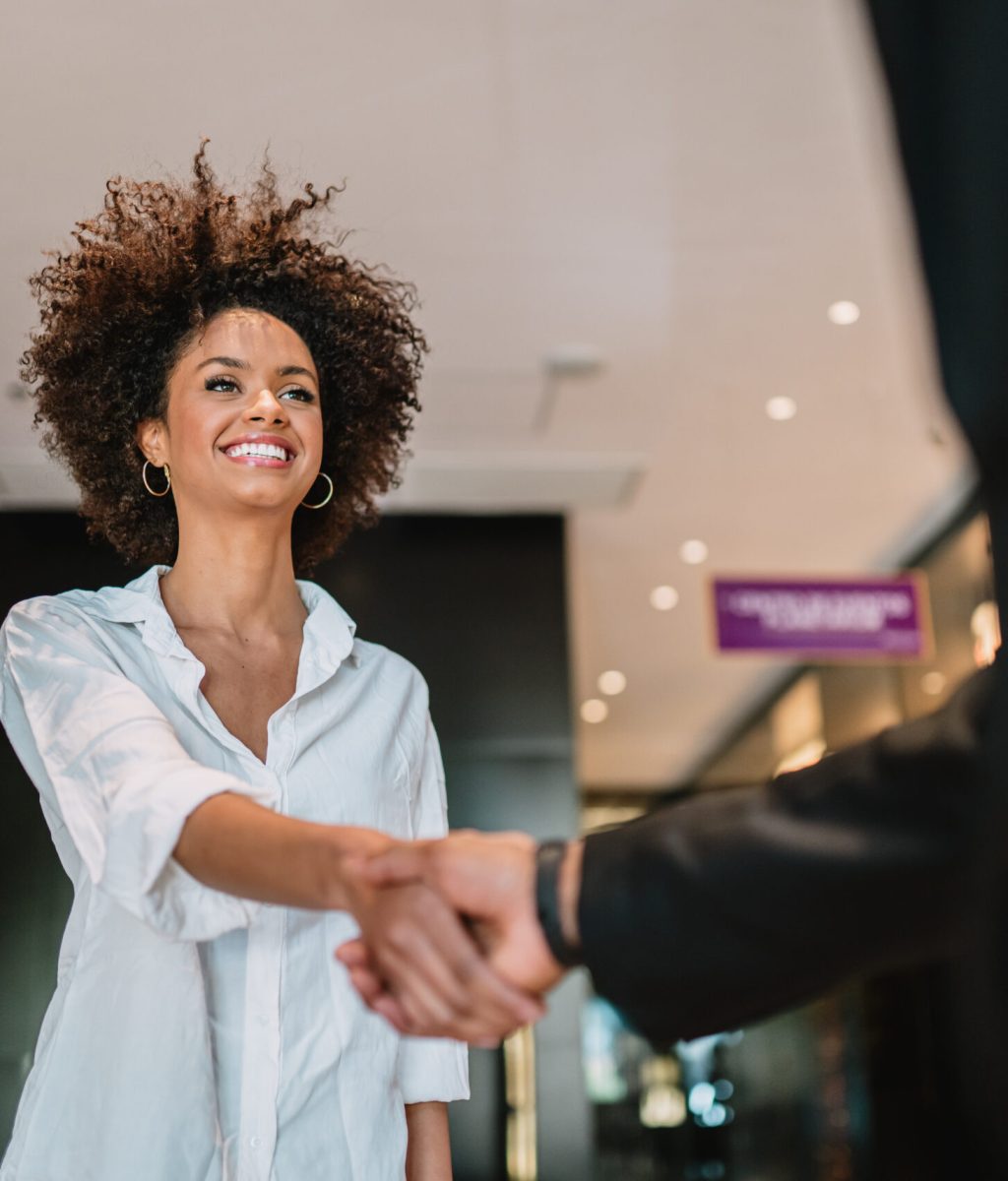 Businessman and woman shake hands like hello in office closeup.